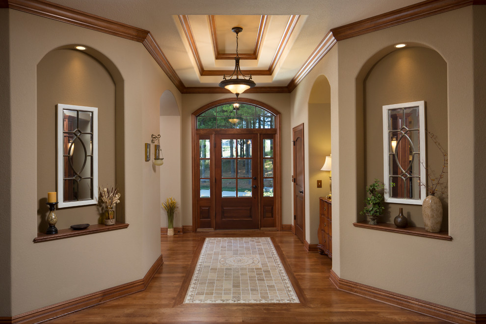 Großes Foyer mit beiger Wandfarbe, dunklem Holzboden, Einzeltür, dunkler Holzhaustür und braunem Boden in Milwaukee