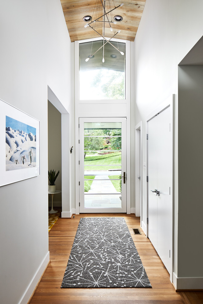 Immagine di un ingresso minimalista di medie dimensioni con pareti bianche, parquet chiaro, una porta singola e una porta in vetro