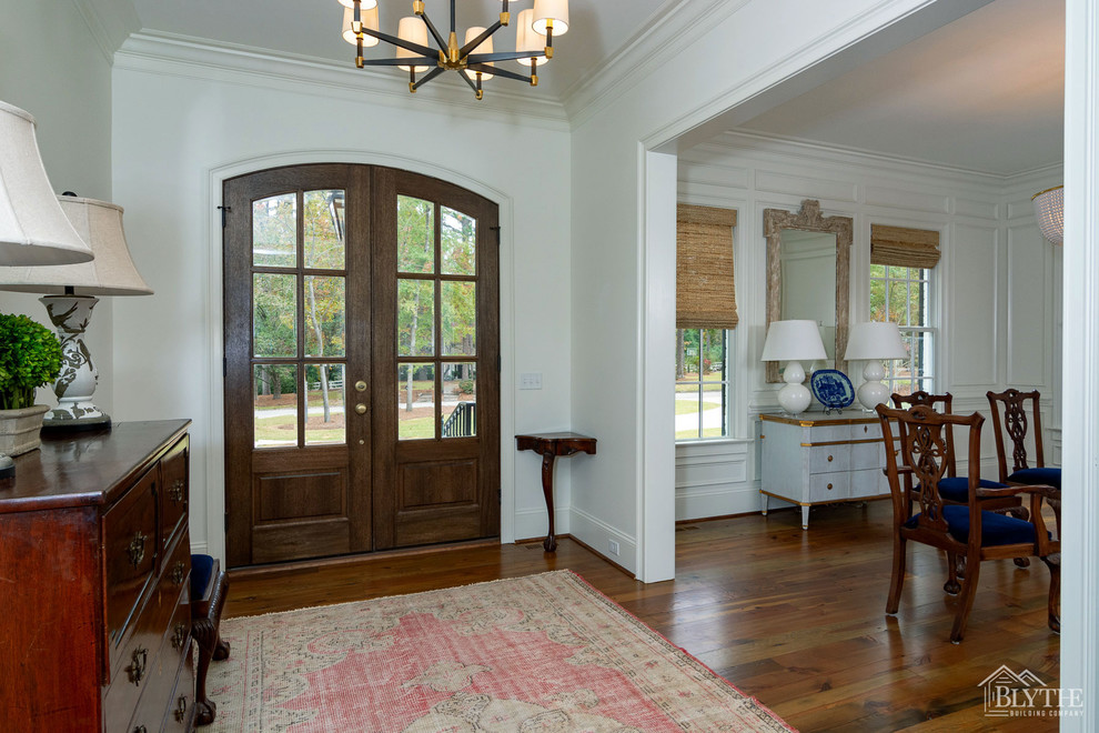 Großes Klassisches Foyer mit weißer Wandfarbe, dunklem Holzboden, Doppeltür, dunkler Holzhaustür und braunem Boden in Sonstige