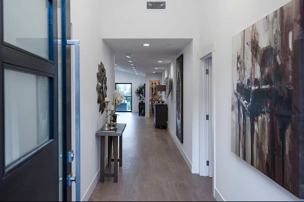 Ispirazione per un ingresso minimalista di medie dimensioni con pareti bianche, parquet chiaro, una porta singola, una porta nera e pavimento marrone