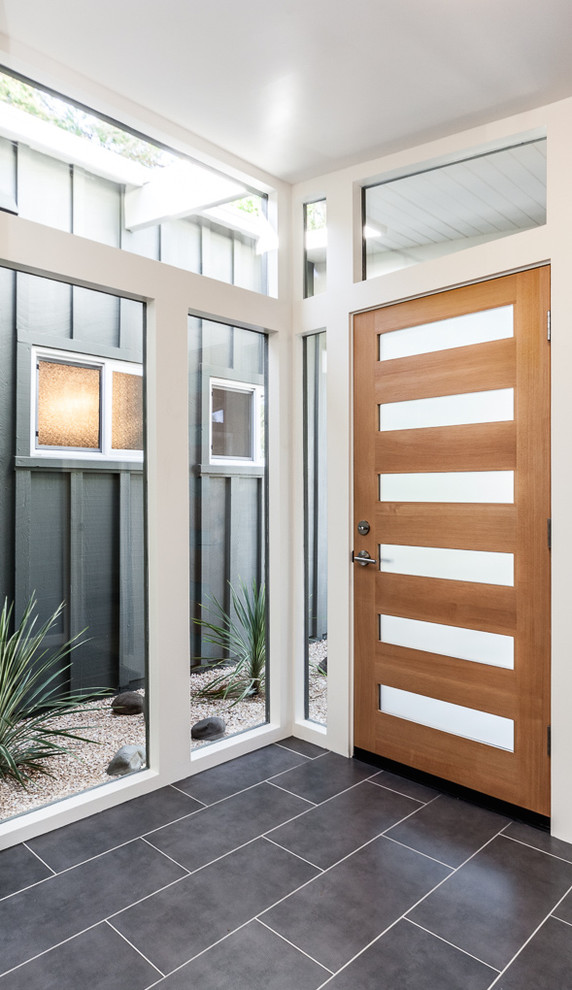 Foto di un ingresso minimalista di medie dimensioni con pareti bianche, pavimento con piastrelle in ceramica, una porta singola e una porta in legno bruno
