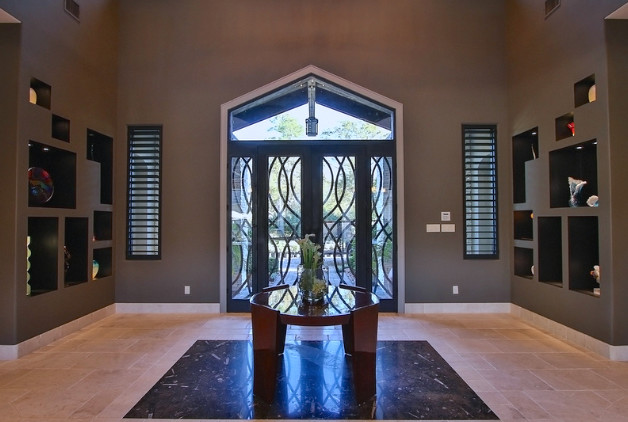 Идея дизайна: огромная входная дверь в стиле неоклассика (современная классика) с коричневыми стенами, мраморным полом, двустворчатой входной дверью и металлической входной дверью