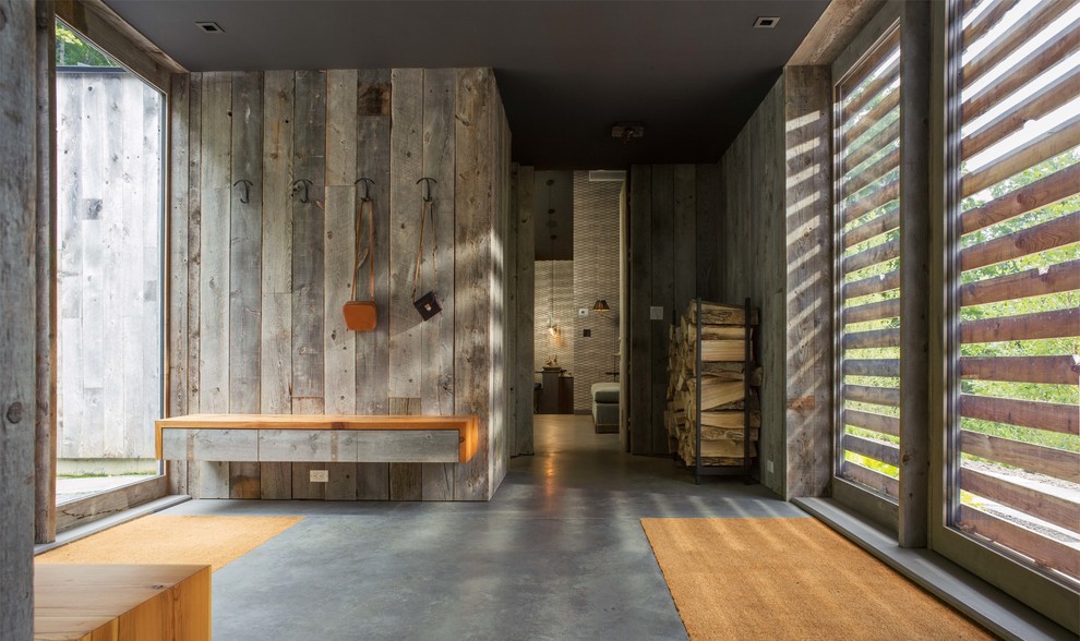 Cette image montre un hall d'entrée design de taille moyenne avec sol en béton ciré, une porte simple, une porte en bois clair et un sol gris.
