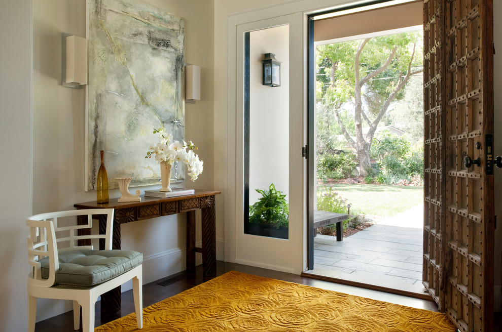 Cette image montre une grande entrée traditionnelle avec un couloir, un mur beige, parquet foncé, une porte simple, une porte en bois brun et un sol marron.