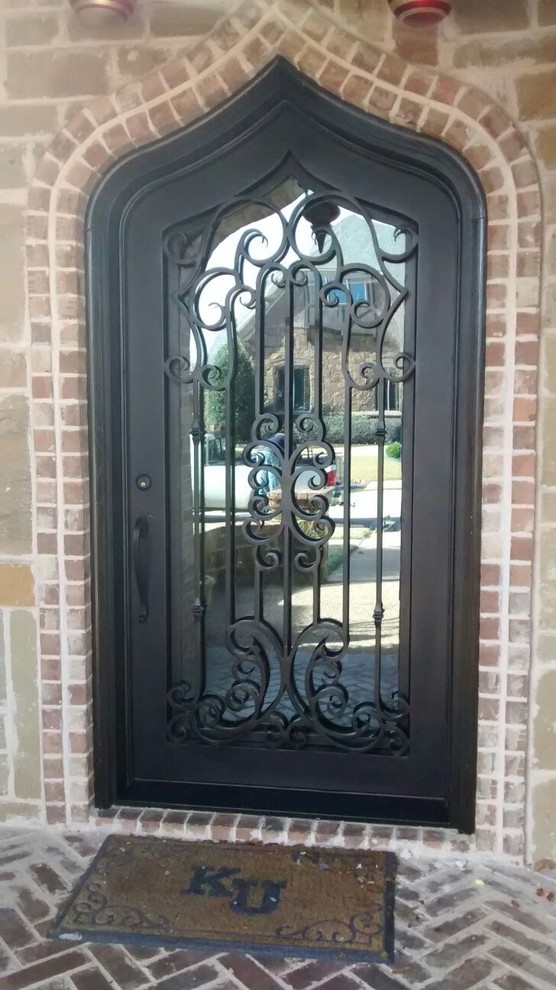 Imagen de puerta principal clásica pequeña con paredes marrones, suelo de cemento, puerta simple y puerta metalizada
