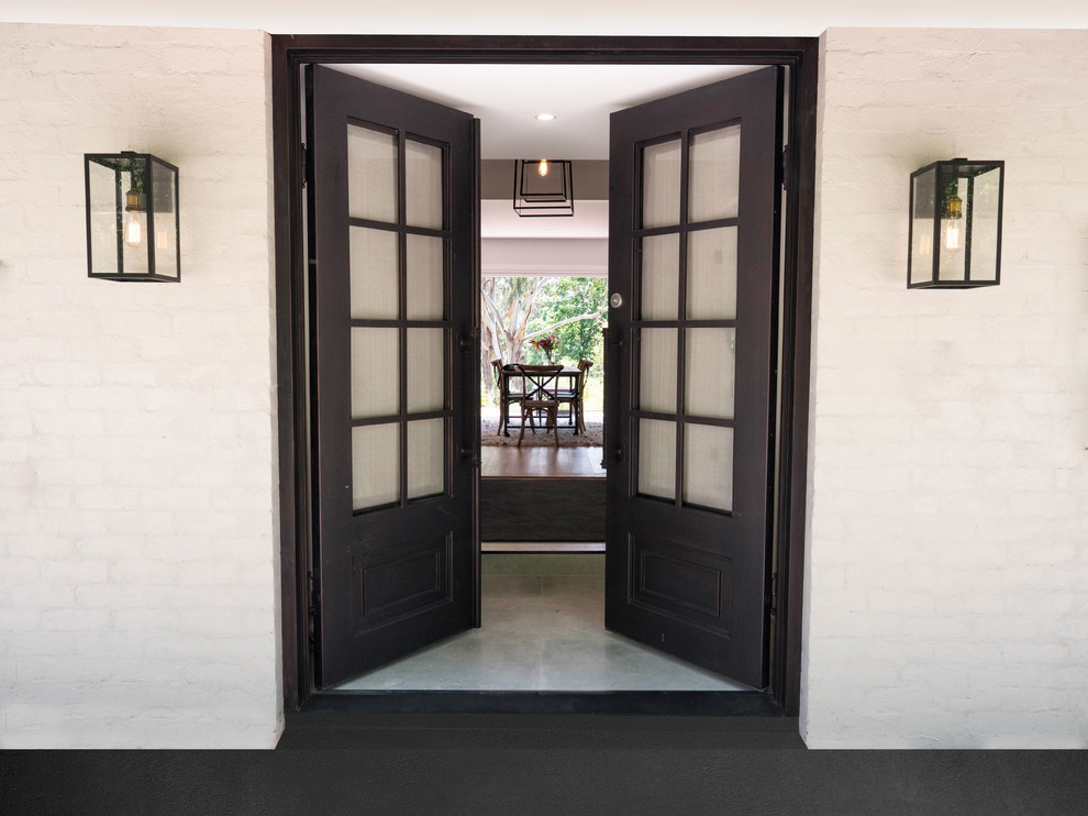 メルボルンにある高級なインダストリアルスタイルのおしゃれな玄関ドア (白い壁、磁器タイルの床、黒いドア、グレーの床) の写真