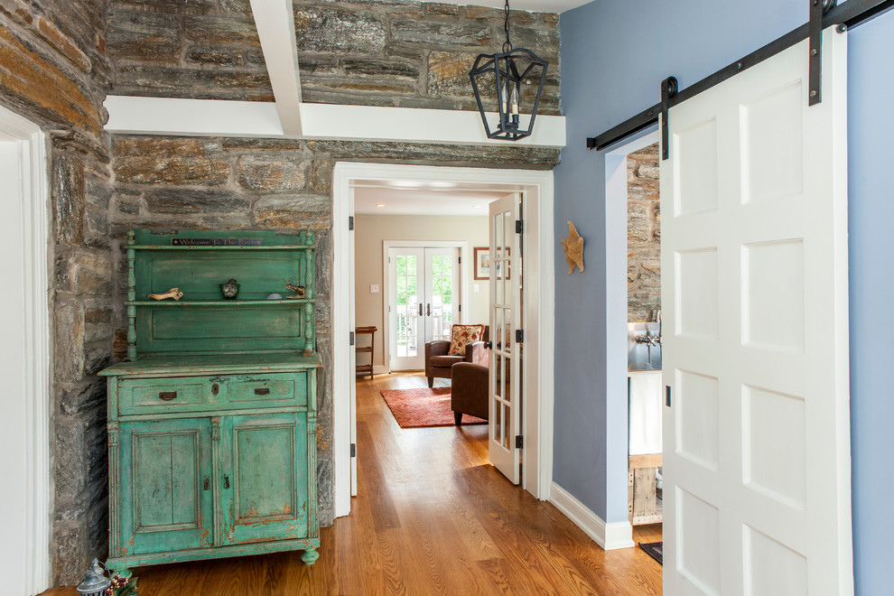 Immagine di un corridoio rustico di medie dimensioni con pareti blu, pavimento in legno massello medio, una porta singola e una porta in legno bruno