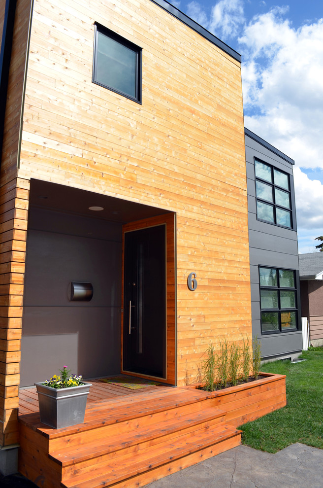 Modelo de entrada minimalista con paredes grises, suelo de madera en tonos medios, puerta simple y puerta negra