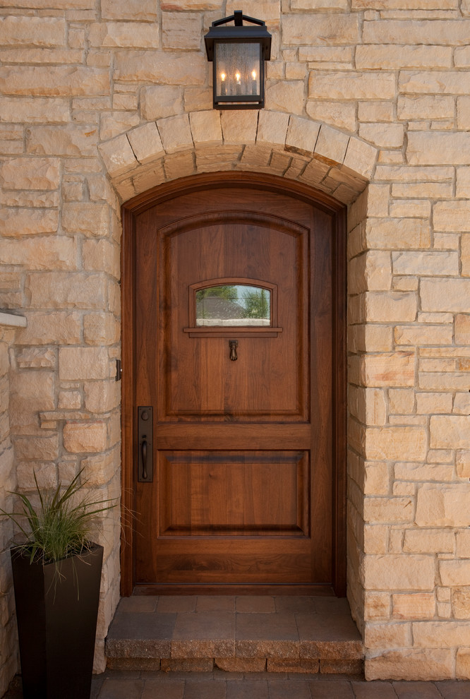 Réalisation d'une grande porte d'entrée tradition avec une porte simple et une porte en bois brun.