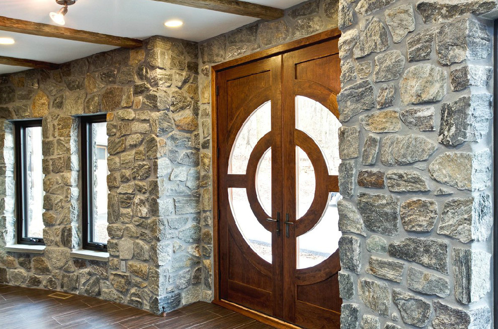 Cette image montre une grande porte d'entrée chalet avec un mur gris, parquet foncé, une porte double et une porte en bois foncé.