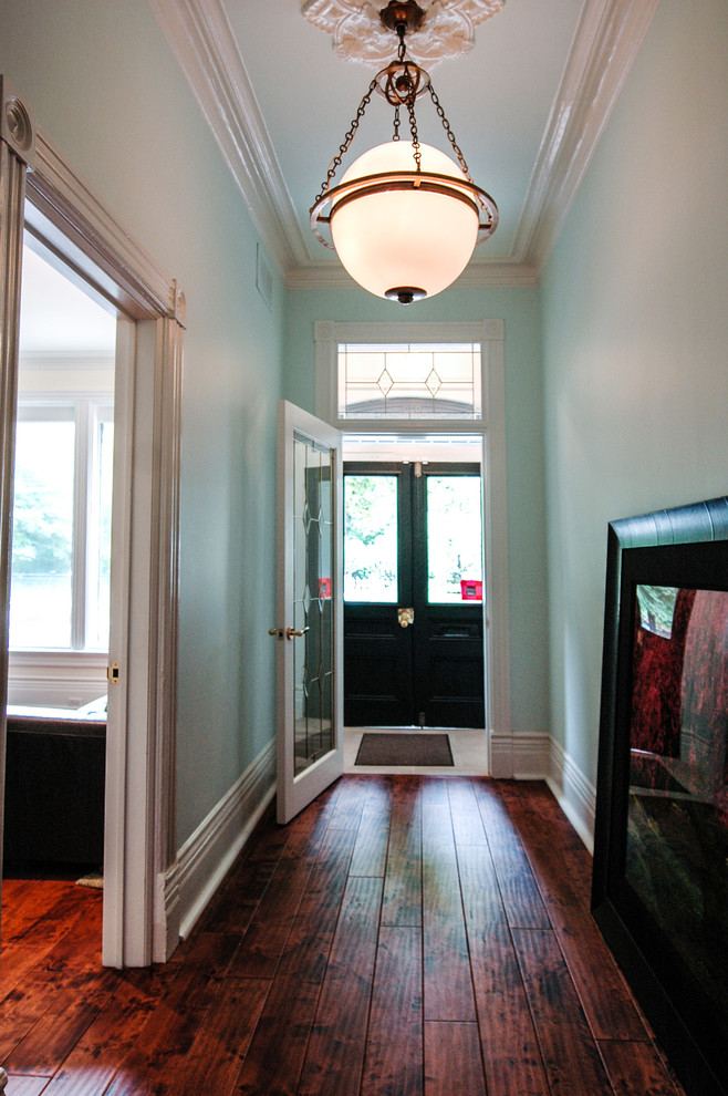 Foto de distribuidor clásico renovado de tamaño medio con paredes azules, suelo de madera en tonos medios, puerta doble y puerta de madera oscura