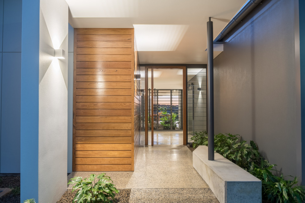 На фото: входная дверь среднего размера в стиле модернизм с серыми стенами, бетонным полом, поворотной входной дверью, входной дверью из дерева среднего тона, серым полом и стенами из вагонки
