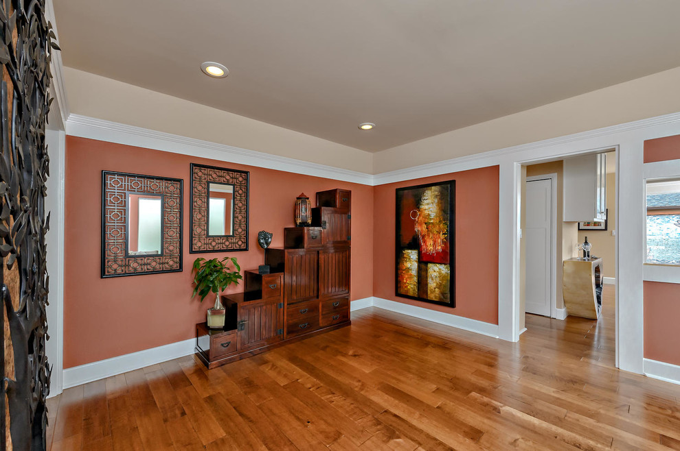Exemple d'un hall d'entrée chic de taille moyenne avec un mur orange, un sol en bois brun, une porte simple et une porte en bois brun.