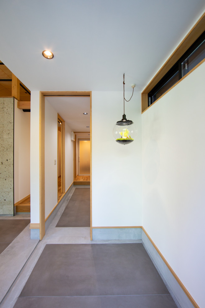 Mittelgroßer Moderner Eingang mit Korridor, weißer Wandfarbe, Porzellan-Bodenfliesen, Einzeltür, schwarzer Haustür und grauem Boden in Sonstige