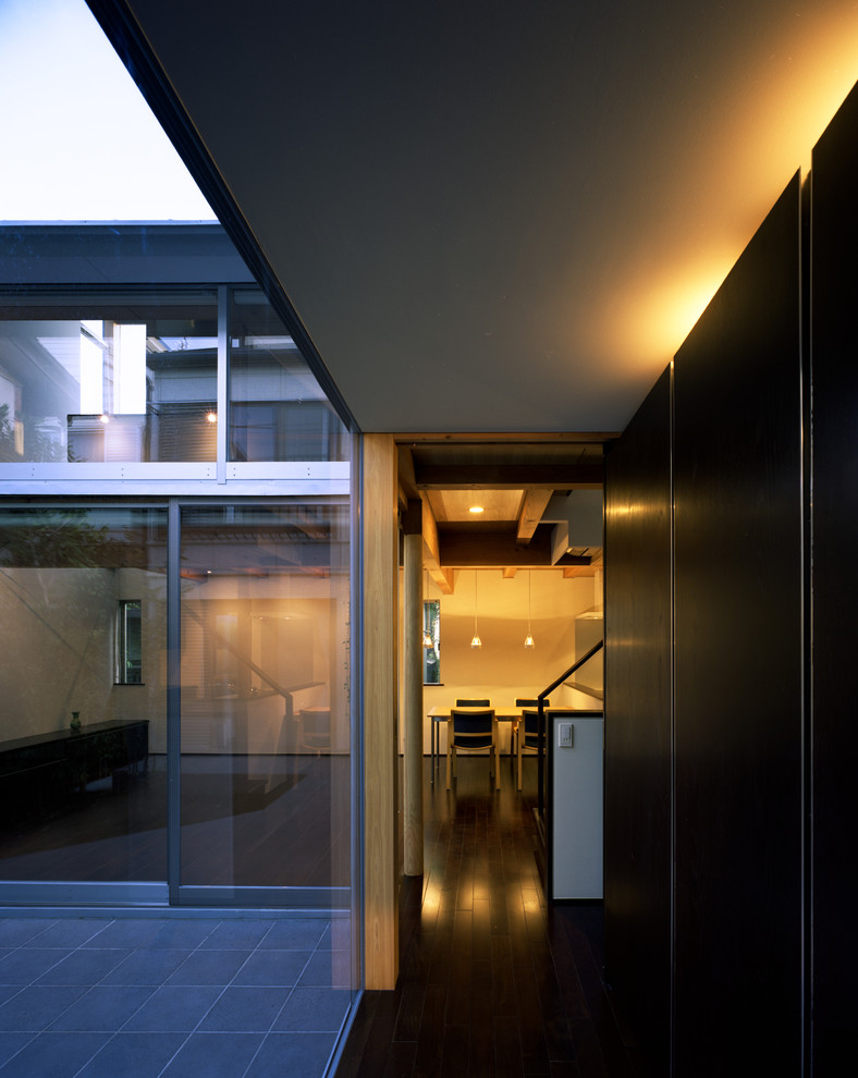 Пример оригинального дизайна: маленькая узкая прихожая в стиле модернизм с белыми стенами, темным паркетным полом, одностворчатой входной дверью, металлической входной дверью и черным полом для на участке и в саду