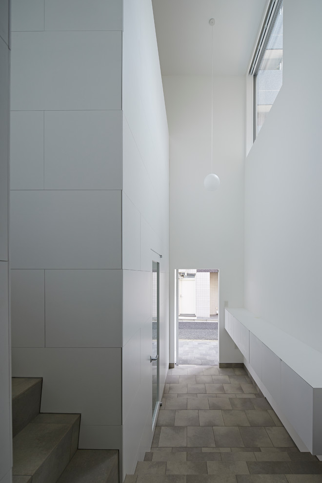 Foto di un corridoio design con pareti bianche, pavimento in gres porcellanato, una porta singola, una porta bianca e pavimento grigio