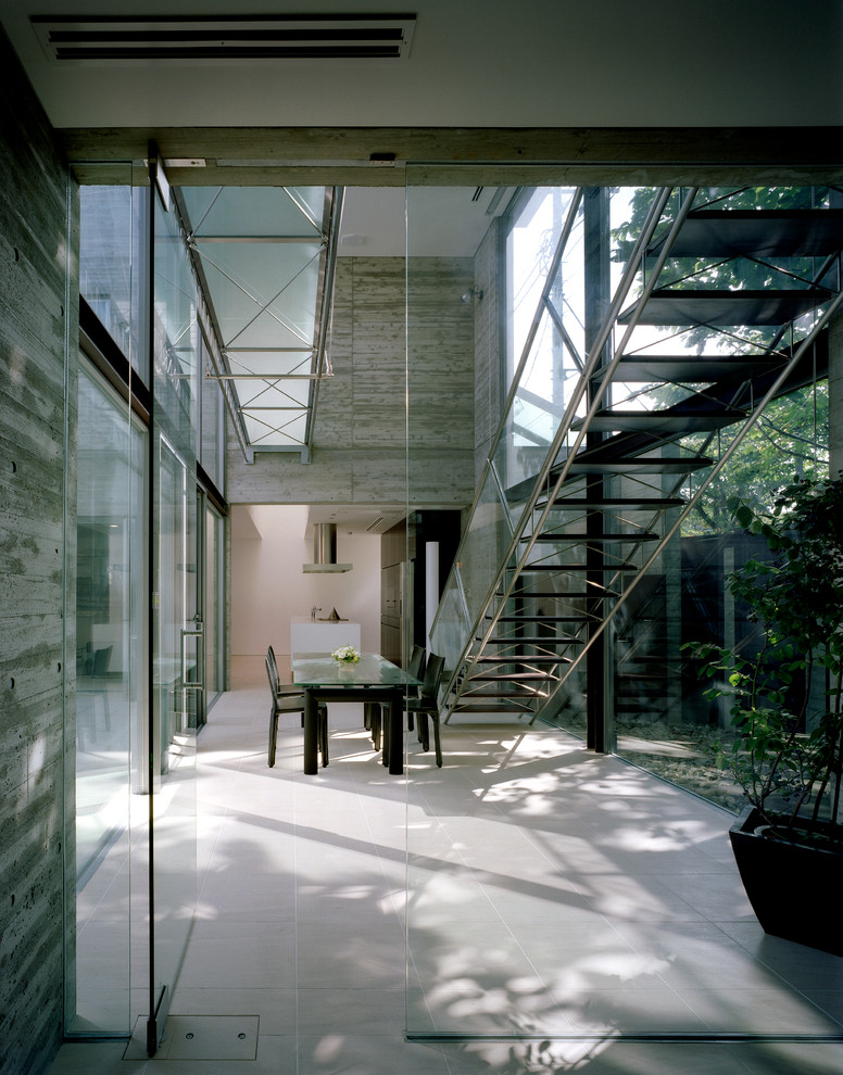 Contemporary entrance in Tokyo with grey walls and a glass front door.