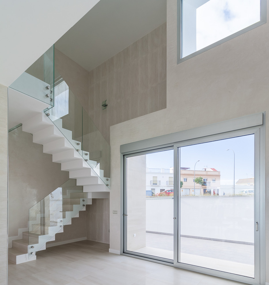 Imagen de escalera en U contemporánea grande con escalones con baldosas, contrahuellas con baldosas y/o azulejos y barandilla de vidrio
