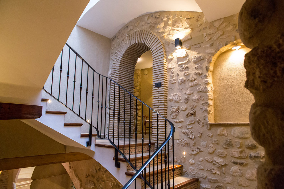 アリカンテにあるラグジュアリーな広いラスティックスタイルのおしゃれな折り返し階段 (テラコッタの蹴込み板、金属の手すり) の写真