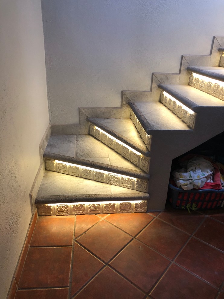 Imagen de escalera en U minimalista de tamaño medio con escalones con baldosas, contrahuellas con baldosas y/o azulejos y barandilla de metal
