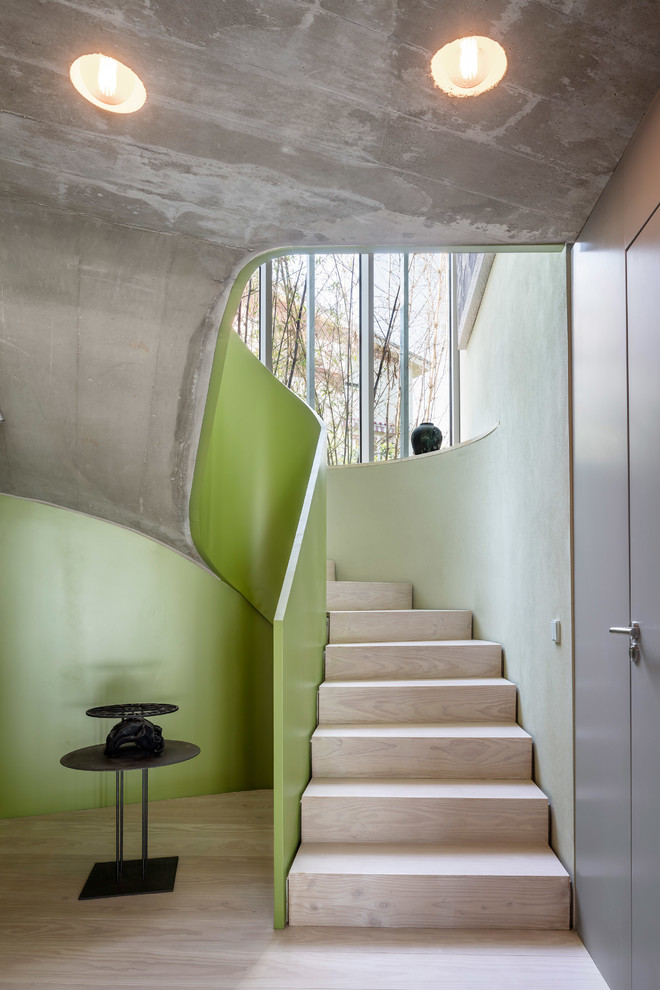 Cette image montre un escalier courbe design avec des marches en bois, des contremarches en bois et éclairage.