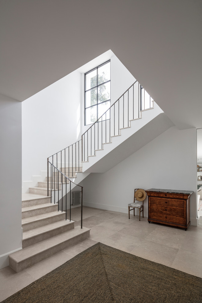 Mittelgroße Treppe in U-Form mit Kalk-Treppenstufen, Kalk-Setzstufen und Stahlgeländer in Sonstige