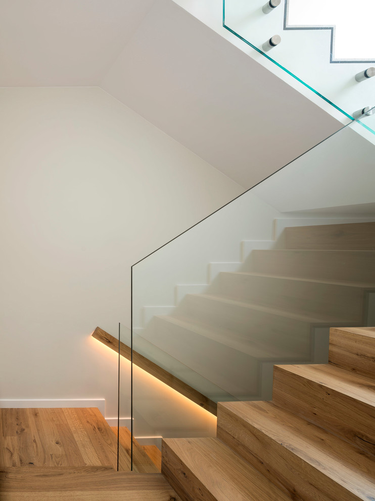 Cette image montre un escalier nordique en U de taille moyenne avec des marches en bois, des contremarches en bois et un garde-corps en verre.