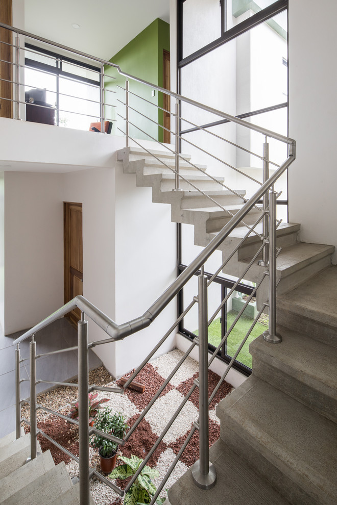 Cette photo montre un escalier moderne en U et béton avec des contremarches en béton et un garde-corps en métal.