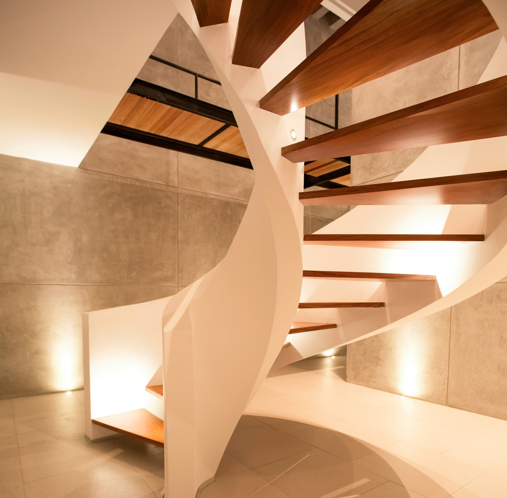 На фото: большая винтовая лестница в современном стиле с деревянными ступенями с