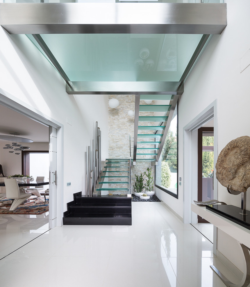 This is an example of a large contemporary glass u-shaped staircase in Seville with open risers.