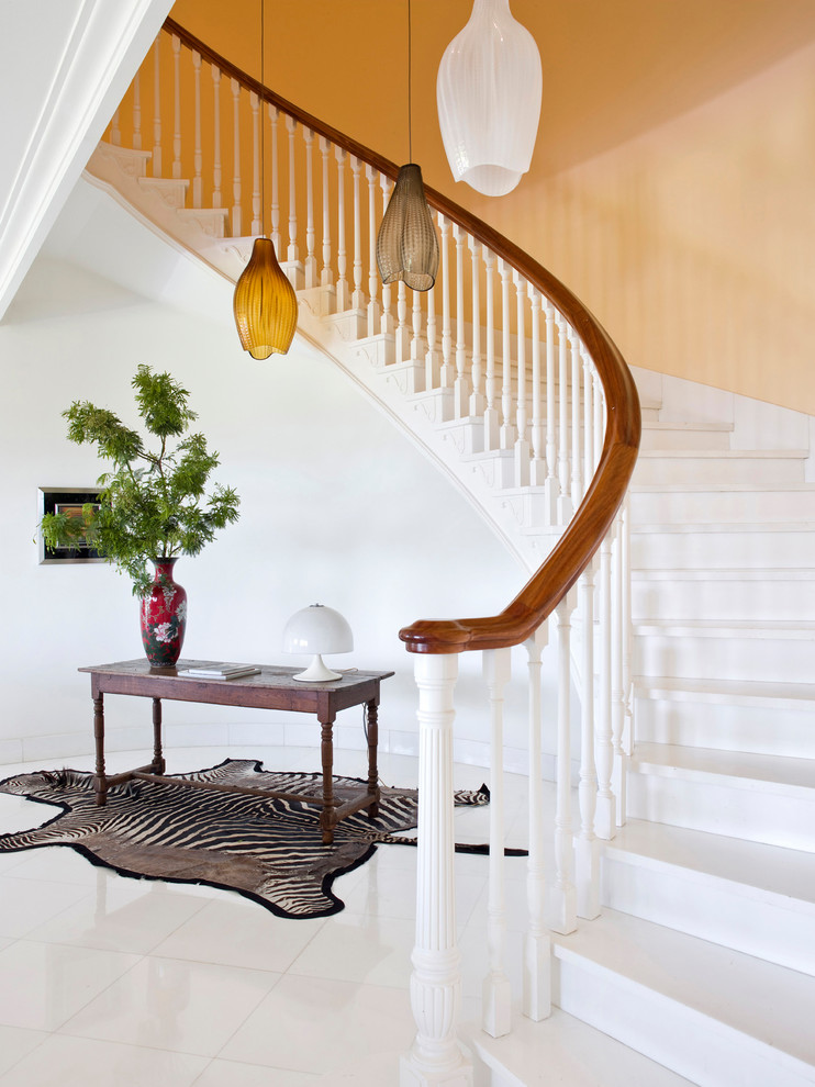 Imagen de escalera curva bohemia con escalones de madera pintada, contrahuellas de madera pintada y barandilla de madera