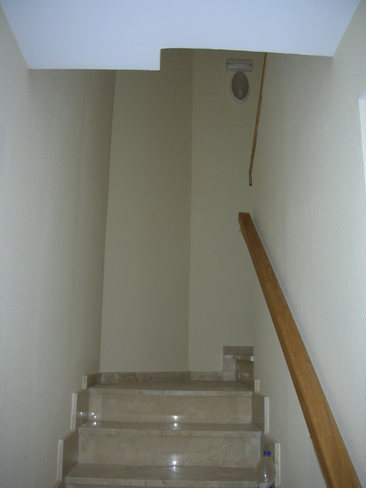 Foto de escalera en U minimalista pequeña con escalones de mármol, contrahuellas de mármol y barandilla de madera