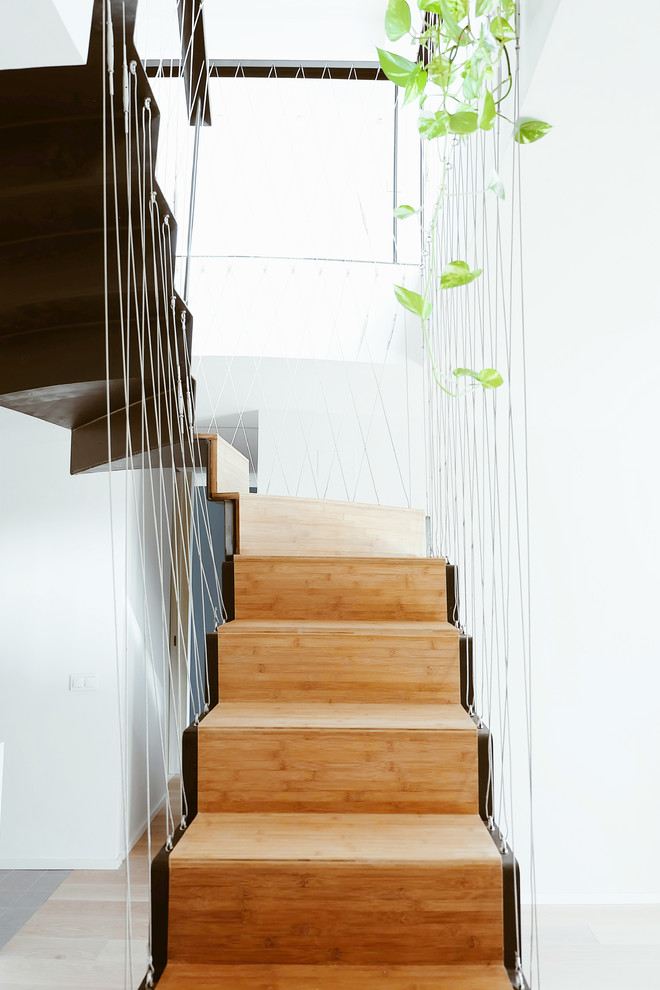 Inspiration for a mid-sized contemporary wooden u-shaped cable railing staircase remodel in Madrid with wooden risers