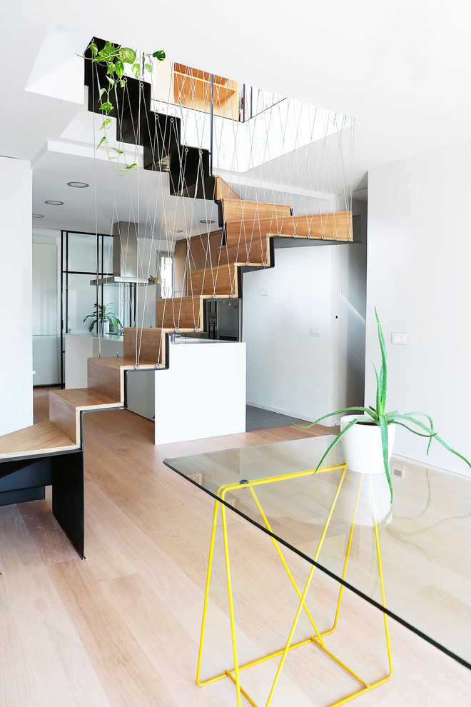 Imagen de escalera en U contemporánea de tamaño medio con escalones de madera, contrahuellas de madera y barandilla de cable