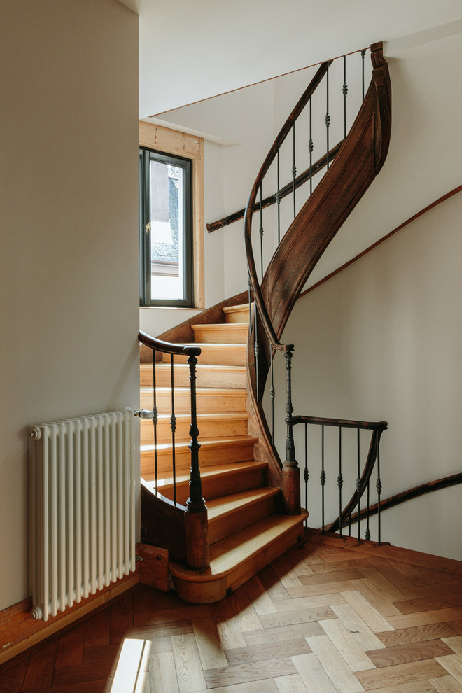 Foto de escalera de caracol tradicional con escalones de madera, contrahuellas de madera y barandilla de metal