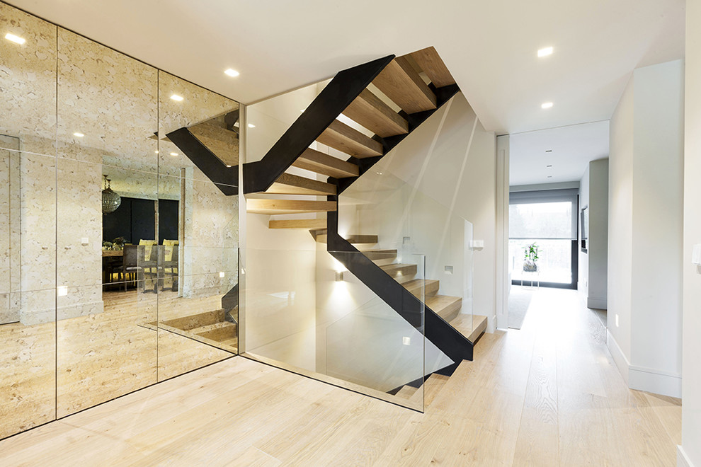 Ejemplo de escalera en U actual sin contrahuella con escalones de madera y barandilla de vidrio