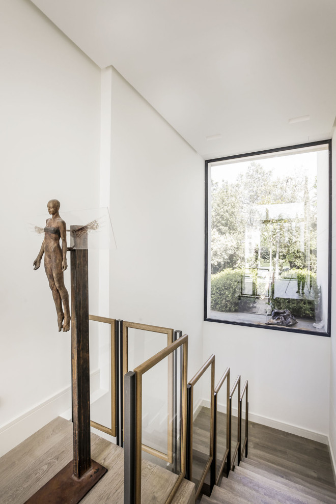 Inspiration for a contemporary wooden u-shaped mixed material railing staircase remodel in Madrid with wooden risers