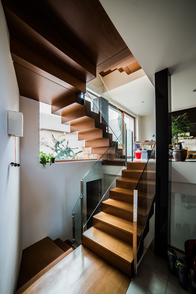 Cette photo montre un grand escalier tendance en U avec des marches en bois, des contremarches en bois et éclairage.