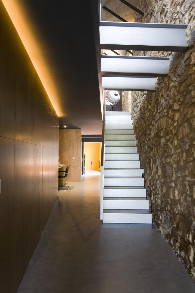 Imagen de escalera recta, rústica, grande, con escalones de metal, contrahuellas de metal y barandilla de metal