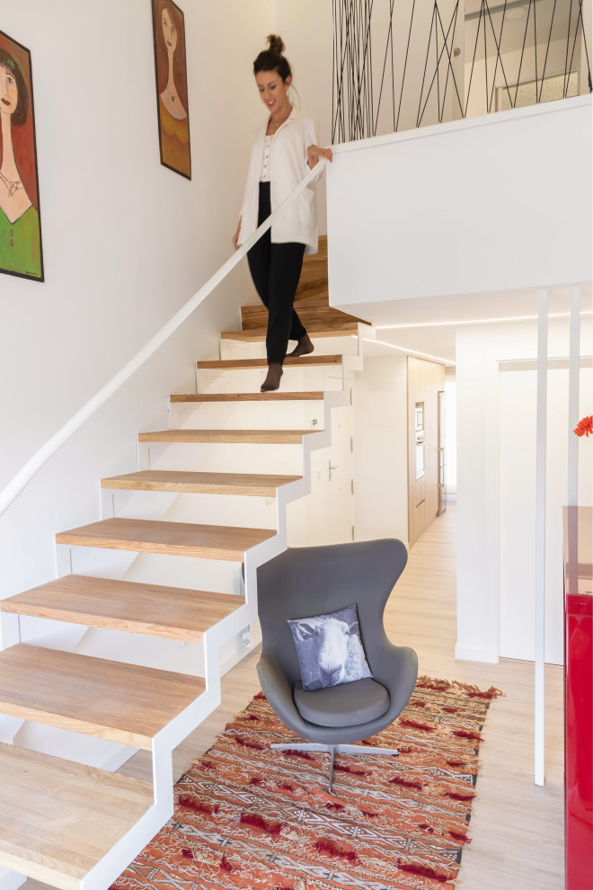 Diseño de escalera suspendida contemporánea sin contrahuella con escalones de madera y barandilla de metal