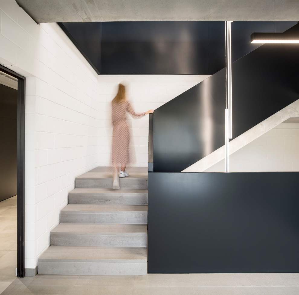 Стильный дизайн: огромная угловая бетонная лестница в стиле лофт с ступенями из плитки и металлическими перилами - последний тренд