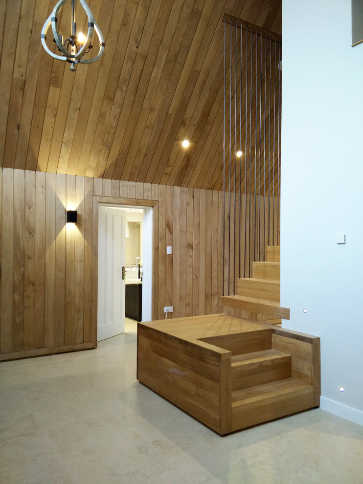На фото: большая деревянная лестница на больцах в скандинавском стиле с деревянными ступенями и металлическими перилами с