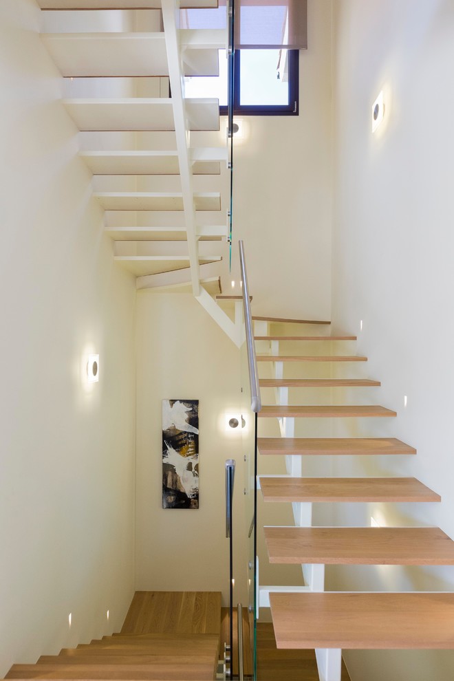Cette image montre un grand escalier sans contremarche flottant minimaliste avec des marches en métal.