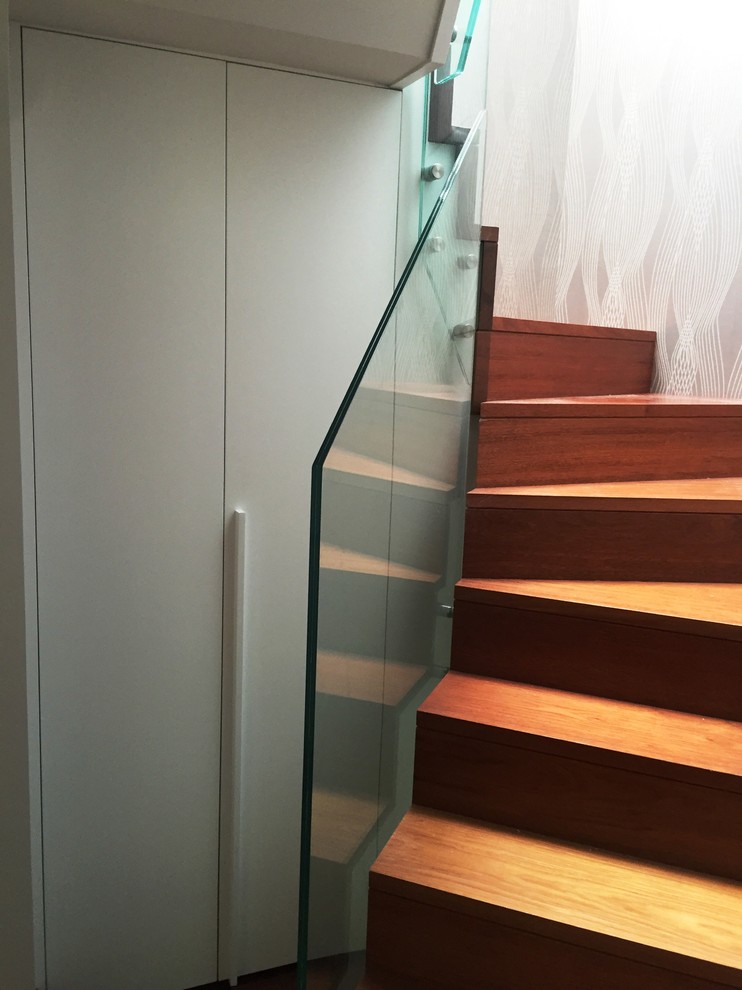 Foto de escalera en U moderna pequeña con escalones de madera, contrahuellas de madera y barandilla de vidrio