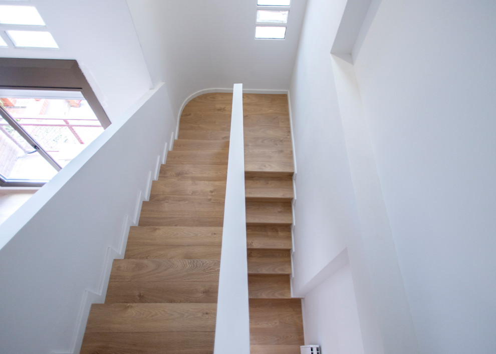 Ejemplo de escalera curva contemporánea grande con escalones de madera, contrahuellas de madera y barandilla de varios materiales