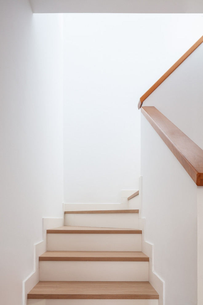 Diseño de escalera en U actual de tamaño medio con escalones de madera, contrahuellas de hormigón y barandilla de madera