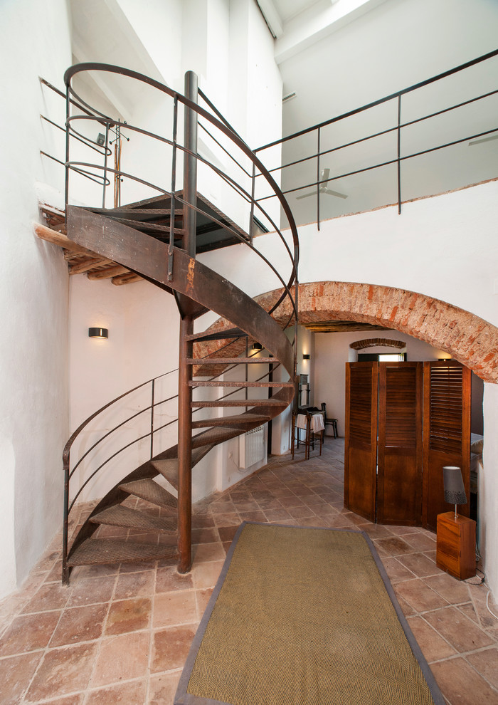 На фото: винтовая лестница среднего размера в средиземноморском стиле с металлическими ступенями без подступенок