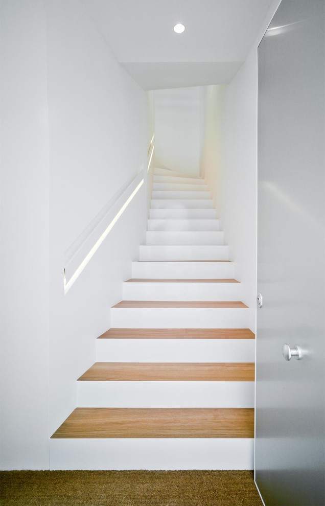 Idées déco pour un grand escalier courbe moderne avec des marches en bois, des contremarches en béton et éclairage.