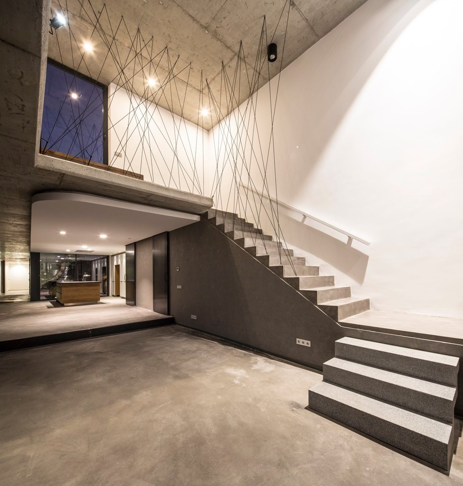 Modern concrete l-shaped staircase in Madrid with concrete risers.