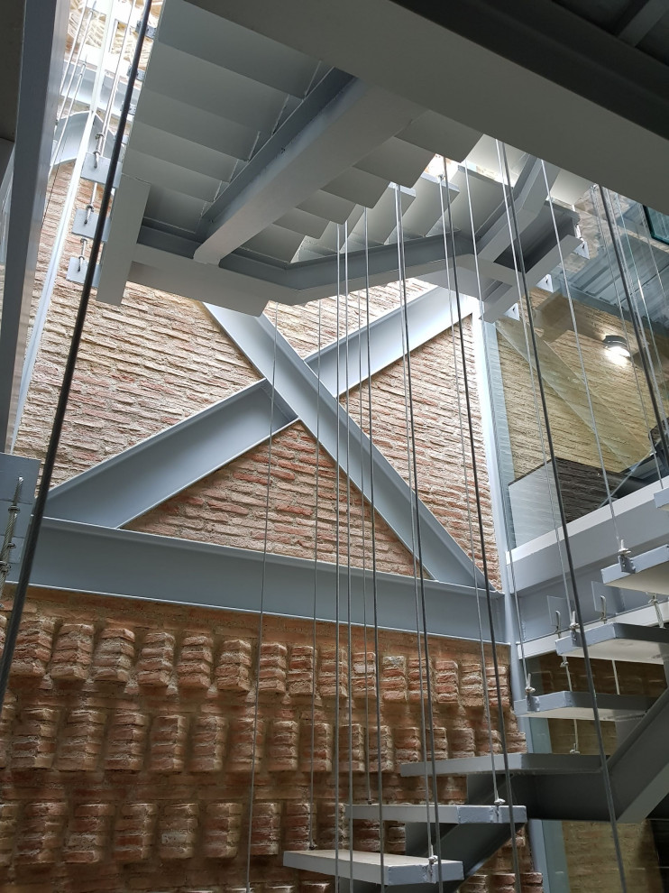 На фото: большая лестница на больцах в современном стиле с бетонными ступенями и кирпичными стенами без подступенок с